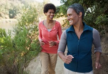 Two women jogging on a wooded trail. 